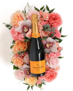 Blush Brilliance-. This exquisite arrangement showcases a harmonious blend of blush and coral roses, accented by elegant orchids and lush greenery-Wine Crate